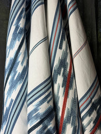 Close-up of a fabric with blue, white, and red striped pattern on a dark background