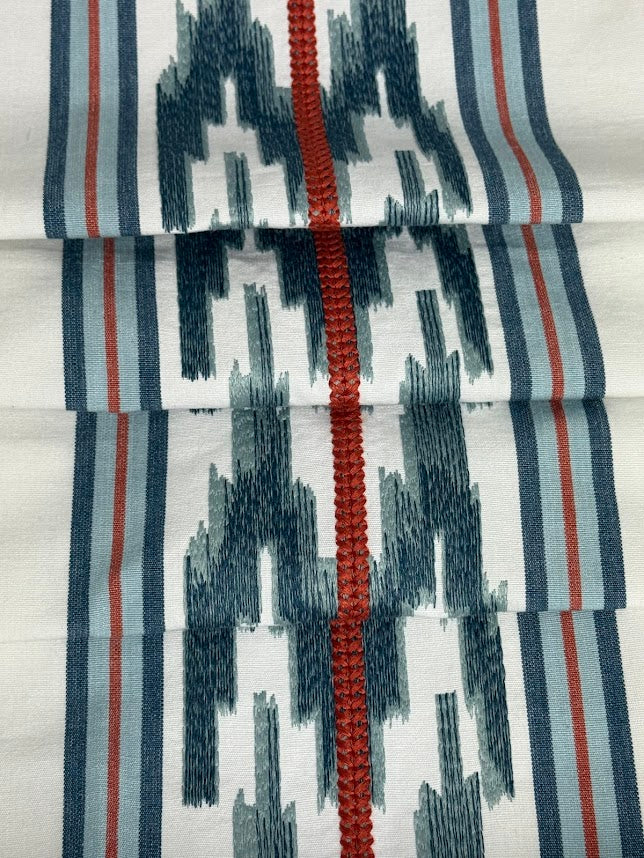 fabric featuring a striped pattern with embroidery in blue and red colors.