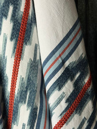 fabric featuring a striped pattern with embroidery in blue and red colors.