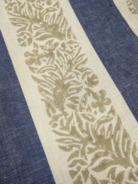 Close-up of a fabric with a leaf pattern on a blue and white striped background