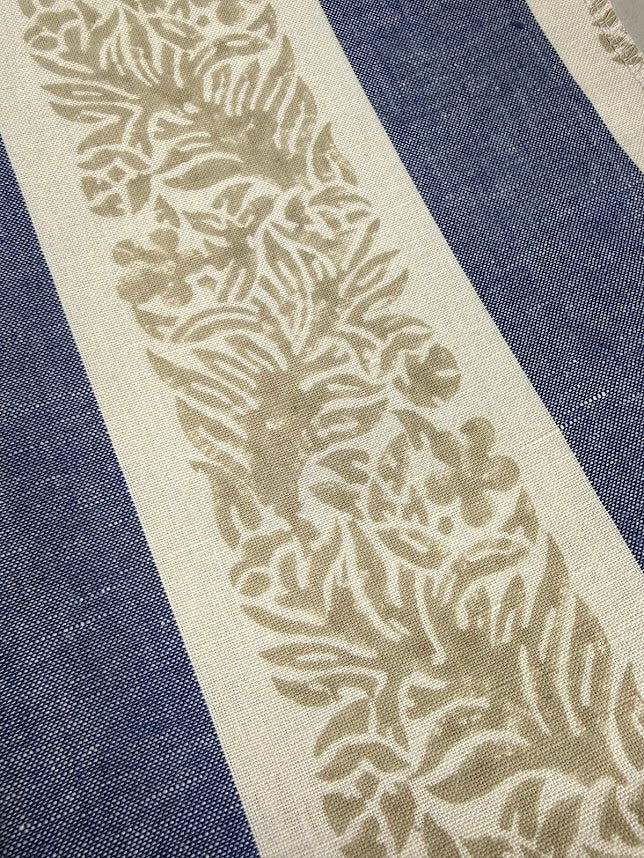Close-up of a fabric with a leaf pattern on a blue and white striped background