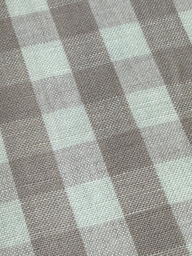 A close-up view of a fabric with a small checkered pattern in shades of lavender and purple.