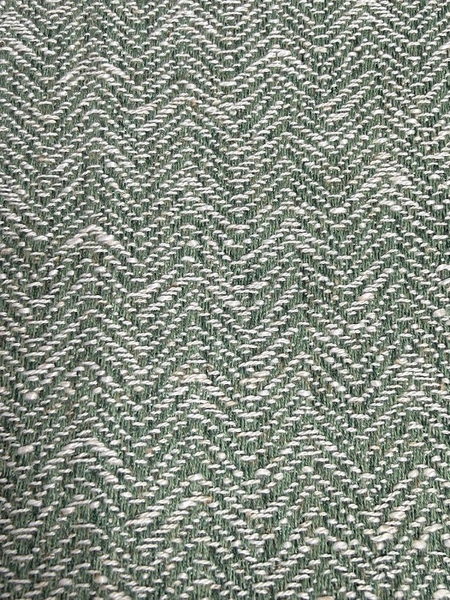 Close-up of a textured green fabric with a herringbone pattern