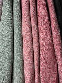 Close-up of textured fabric with a herringbone pattern in green and pink.