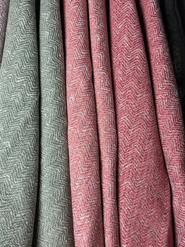 Close-up of textured fabric with a herringbone pattern in green and pink.