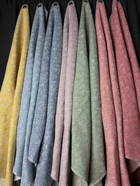 Set of textured fabric samples in various colors hanging against a dark background.