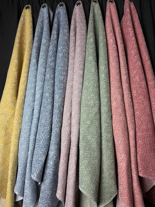 Set of textured fabric samples in various colors hanging against a dark background.