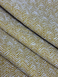 Close-up of a textured fabric with a herringbone pattern in yellow and white.