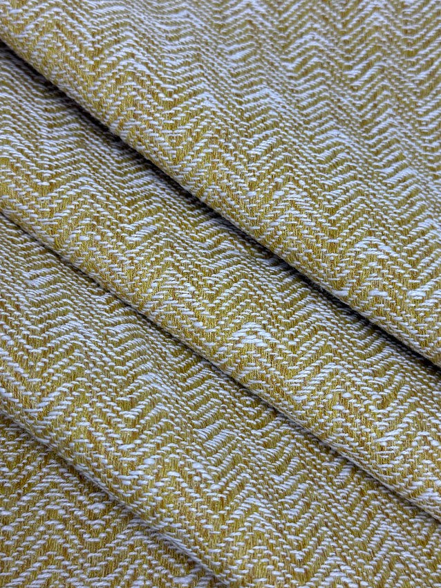 Close-up of a textured fabric with a herringbone pattern in yellow and white.