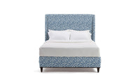 Bed with blue patterned headboard and white bedding on a white background