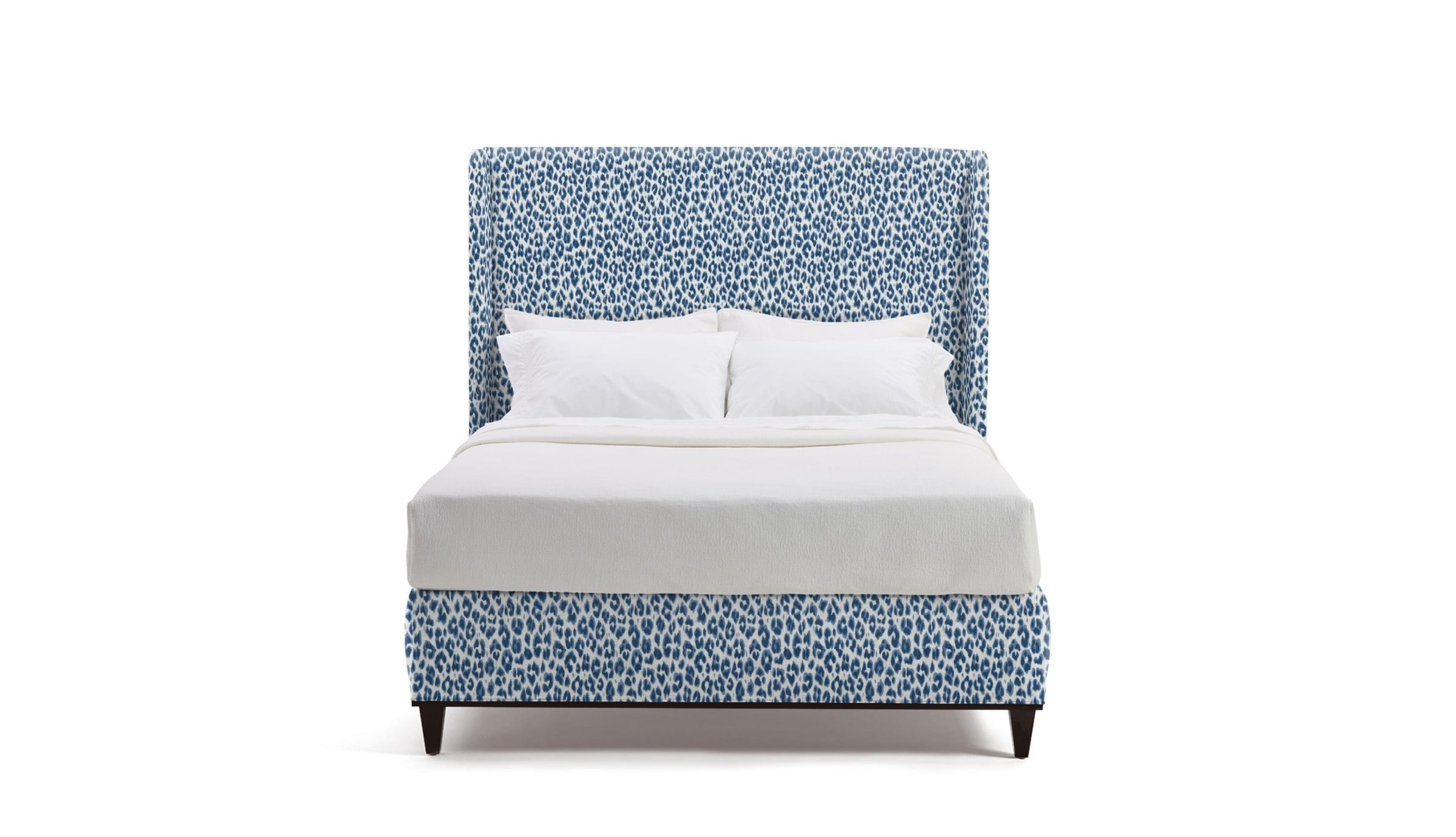 Bed with blue patterned headboard and white bedding on a white background
