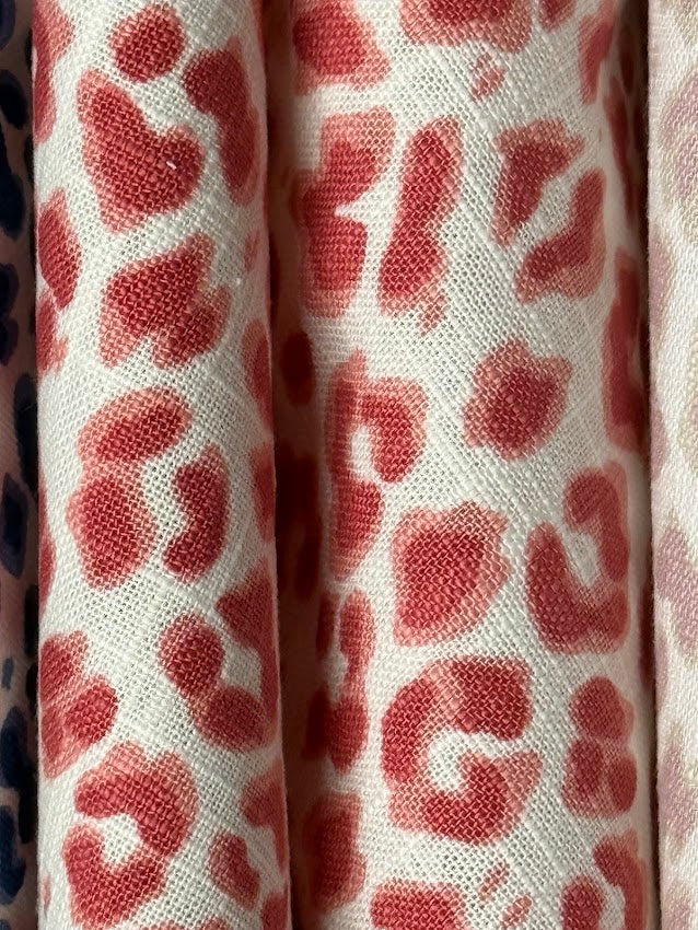Close-up of fabric with red leopard print pattern on a white background
