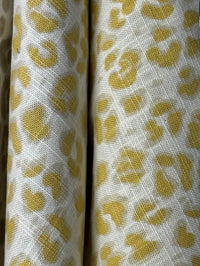 Two rolls of fabric with a yellow leopard print pattern on a white background.