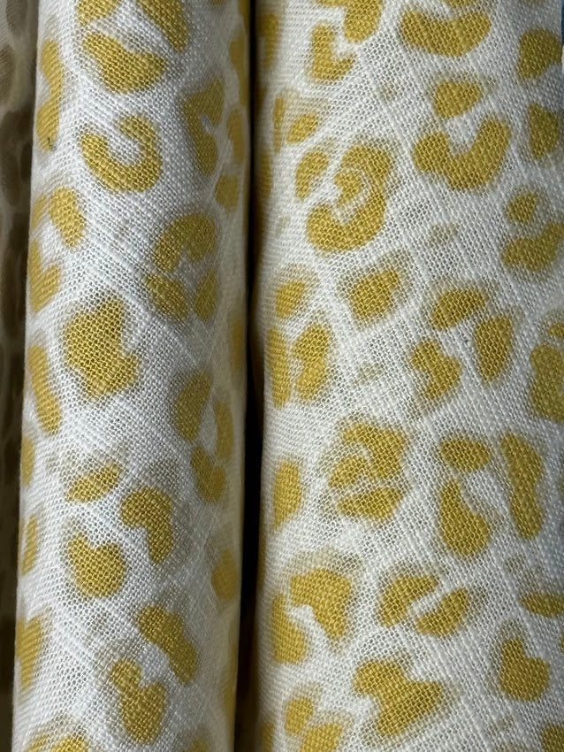Two rolls of fabric with a yellow leopard print pattern on a white background.
