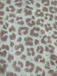 Close-up of fabric with lavender leopard print pattern on a light background