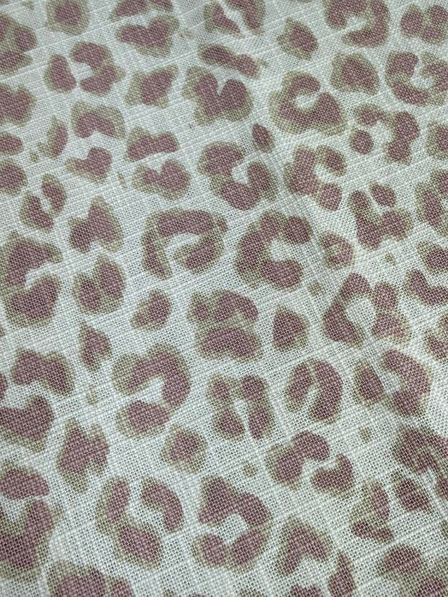 Close-up of fabric with lavender leopard print pattern on a light background