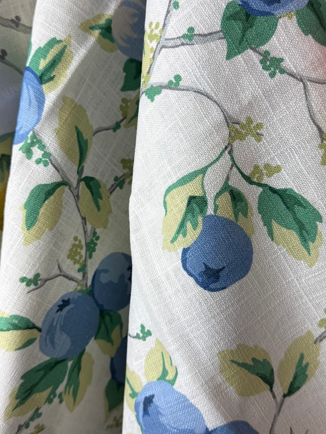 Fabric with blue fruit and green leaves pattern on a white background