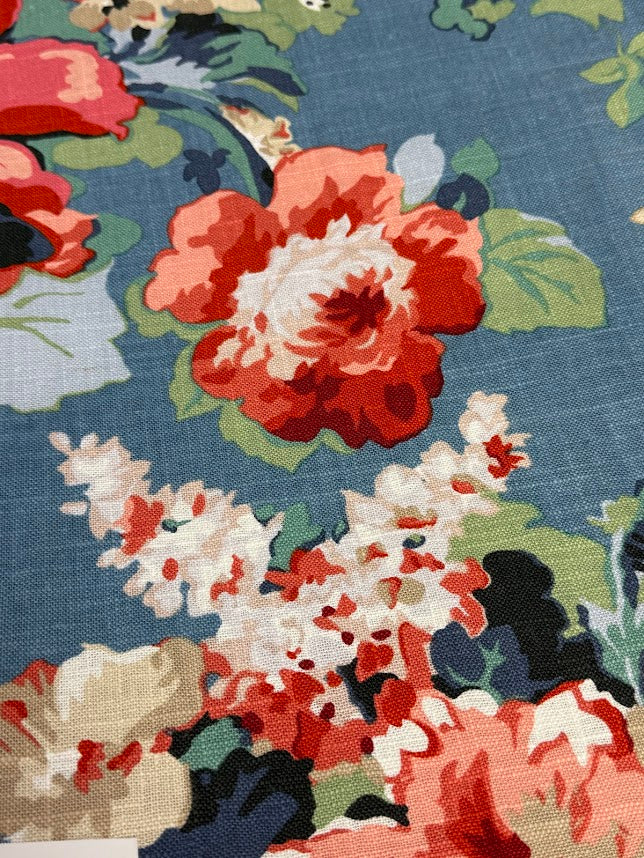 Close-up of a floral fabric pattern with red, white, and green flowers on a blue background.