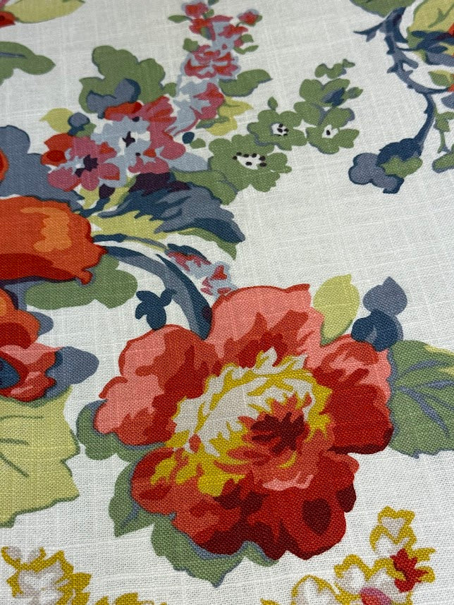 Close-up of a floral fabric pattern with red, yellow, and green flowers on a white background.