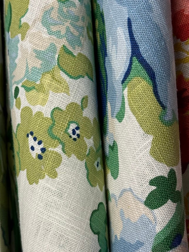 fabric featuring a floral pattern with large blue flowers and green leaves on a white background.