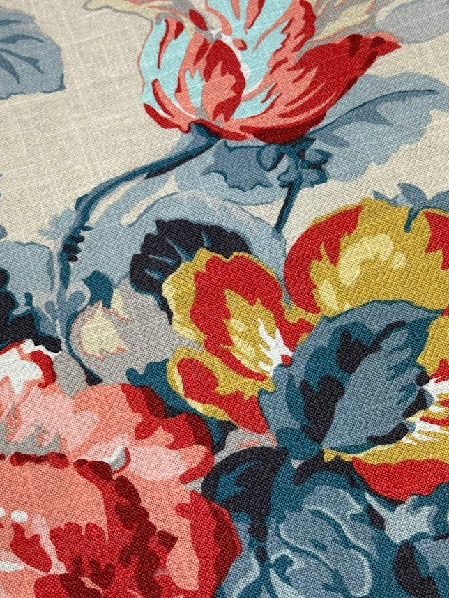 Close-up of a floral patterned rug with red, yellow, and blue flowers on a beige background.