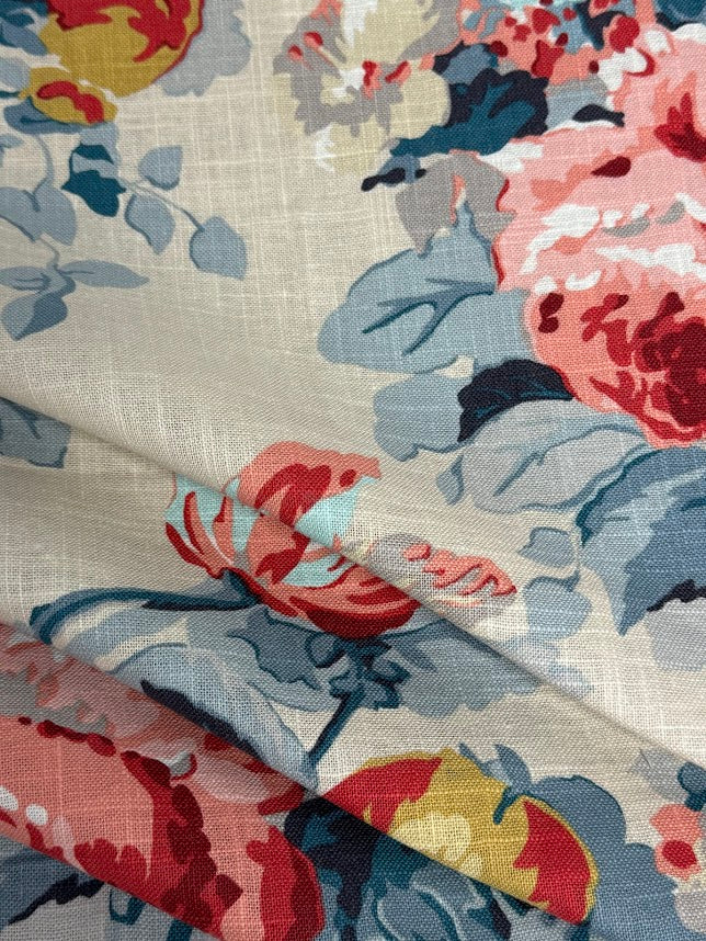 Close-up of floral fabric with red, blue, and pink flowers on a beige background