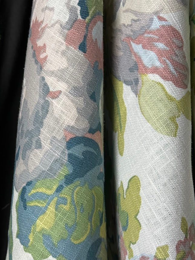 A fabric with a large floral pattern featuring colors such as lavender, purple, green, pale blue, and pink.