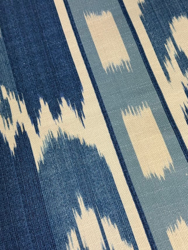 close up of fabric featuring a French blue geometric pattern with vertical stripes and large scale flame stitch design.