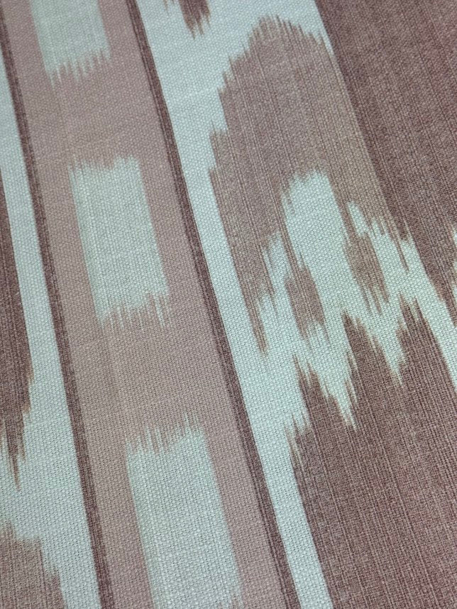 close up fabric featuring a vertical flame stitch pattern with geometric designs in pink and white colors 
