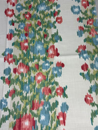 Close-up of a floral patterned fabric with red, blue, and green colors on a white background.