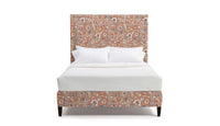 Upholstered bed frame in floral fabric with pink, red, and white flowers on a coral background
