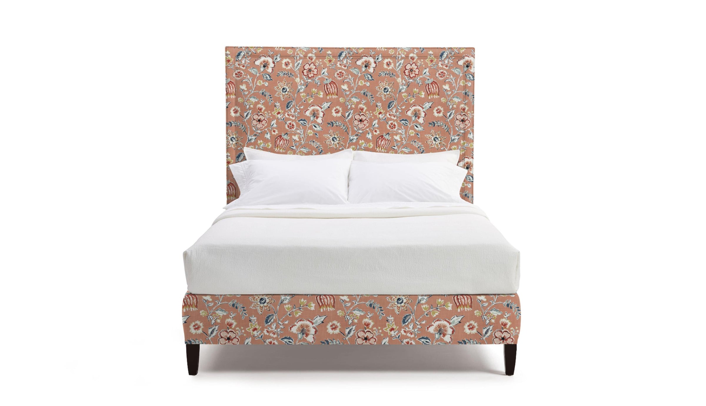 Upholstered bed frame in floral fabric with pink, red, and white flowers on a coral background