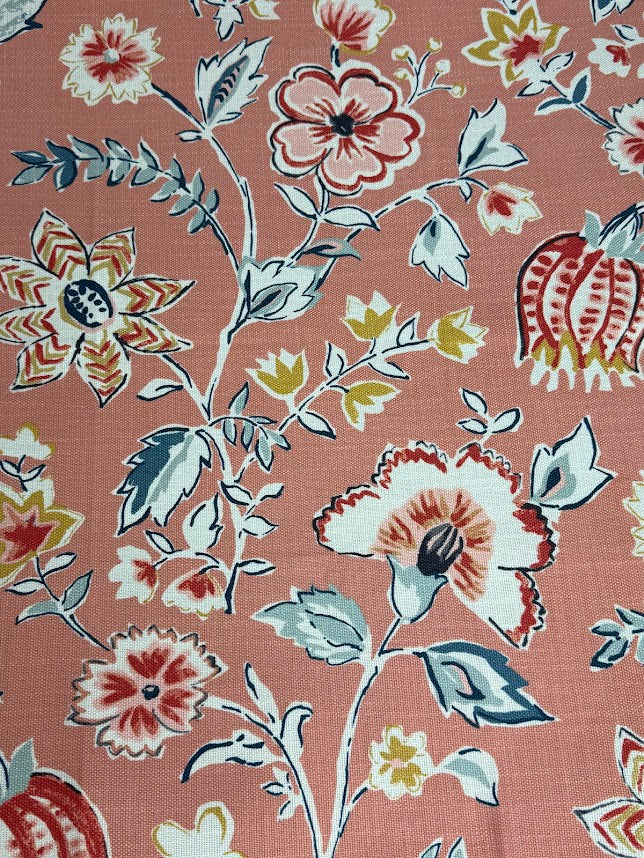 Floral patterned fabric with red, white, and beige flowers on a pink background