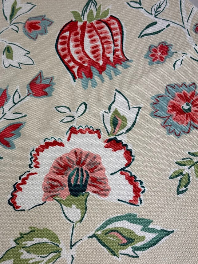 Close-up of floral fabric pattern with red, white, and green colors on a beige background.