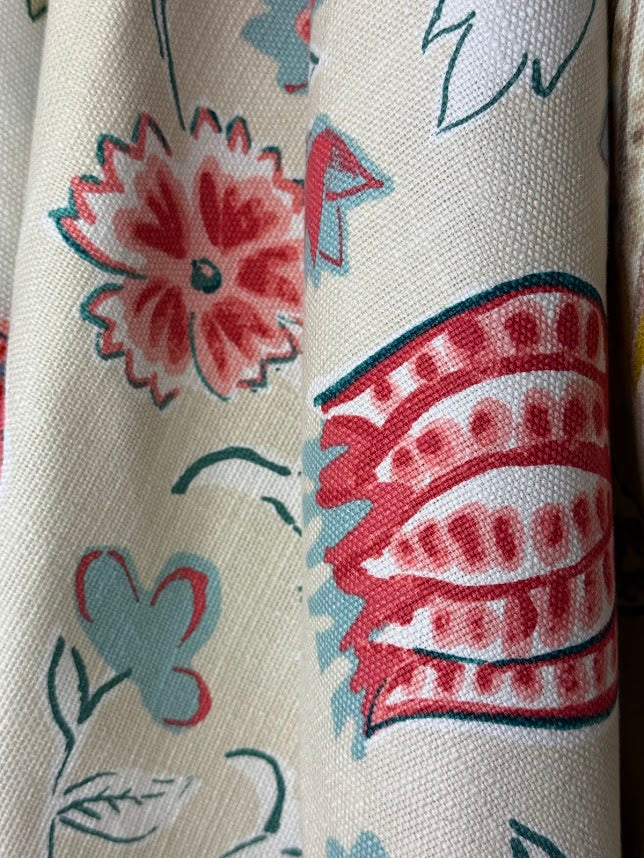 Close-up of floral and abstract patterned fabric with red, blue, and beige colors.