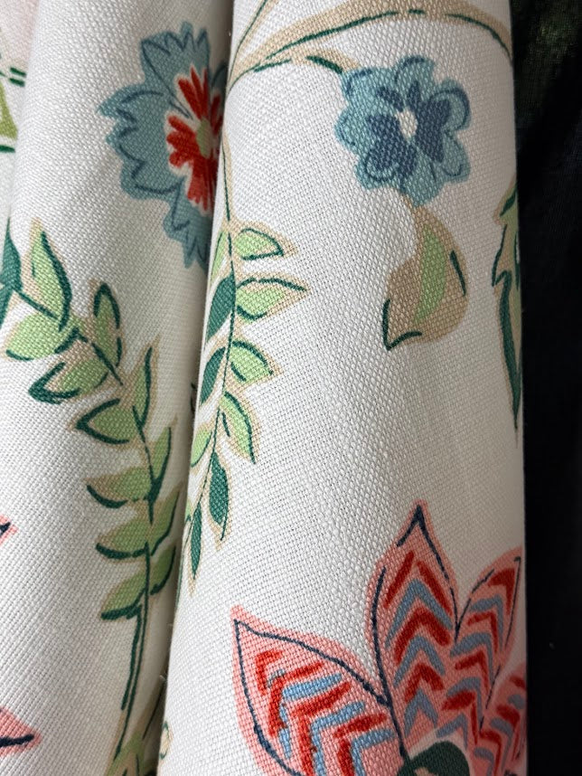 Close-up of floral fabric with blue, green, and red colors on a white background.