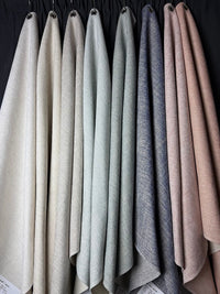 Set of fabric swatches in various neutral colors hanging against a dark background.