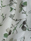 Floral patterned fabric with green leaves and branches on a light background