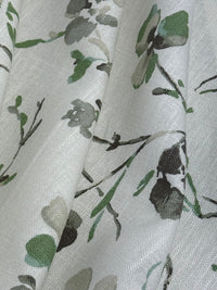 Floral patterned fabric with green leaves and branches on a light background