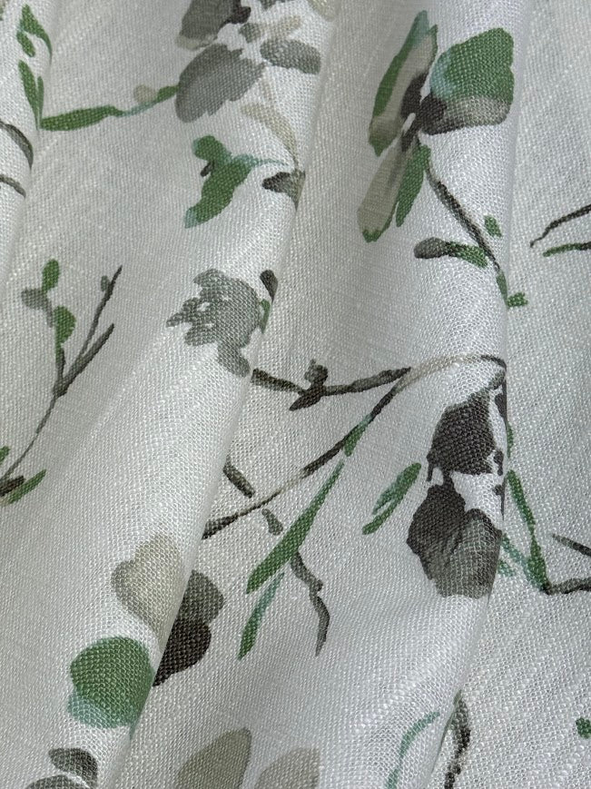 Floral patterned fabric with green leaves and branches on a light background